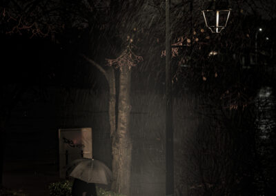A quiet urban moment caught in the rain, under the warm glow of a streetlamp.